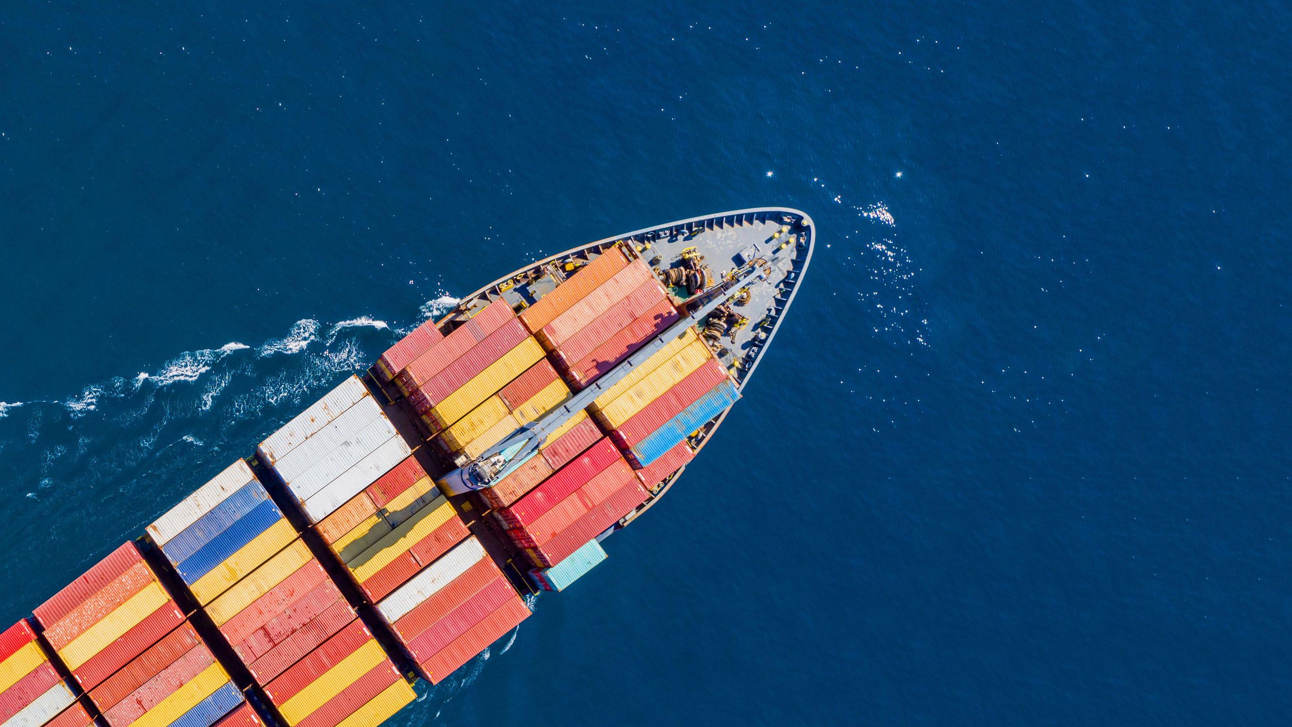 An ariel view of a cargo ship sailing through the ocean