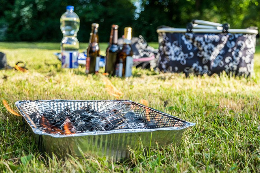 A disposable BBQ alight during a countryside picnic